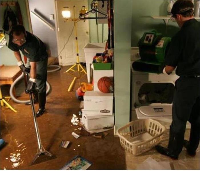 Two men cleaning a flooded basement