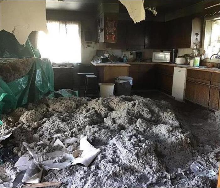 Pile of mud inside a kitchen area due to storm damage, ceiling collapsed